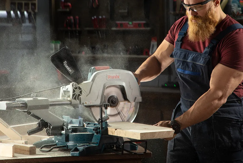 a woodworker is cutting a wood piece with a miter saw