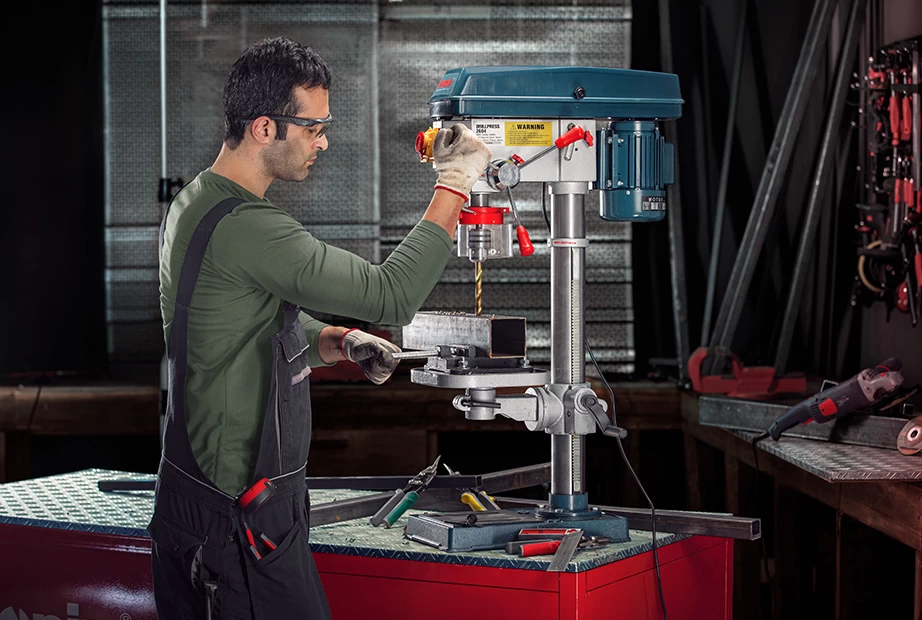 a man using a bench-top drill press