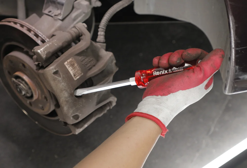 person using a screwdriver on a car wheel