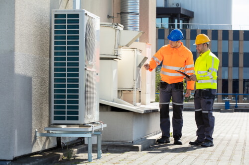 Two worker servicing a commercial HVAC unit using safety equipment